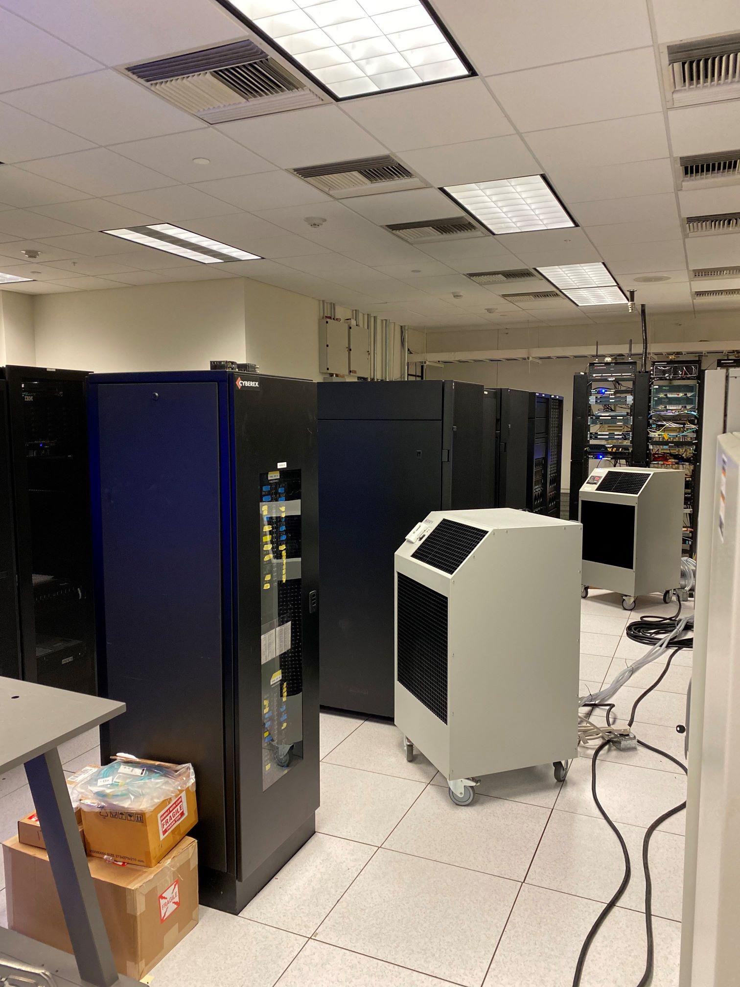 A view of two 60,000 BTU units with electrical and water lines connected inside a server room cooling network equipment during permanent AC repair.  